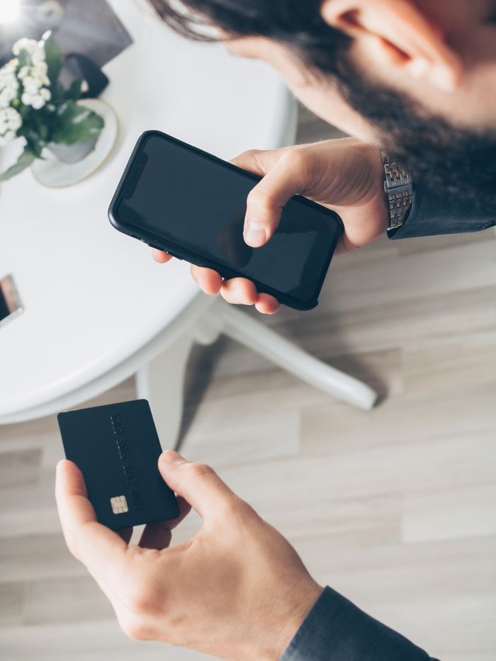 A man using a smartphone and credit card for an online payment, showcasing digital finance concepts.